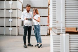 Homem e mulher dentro de um armazém de Self Storage, conversando sobre dados apresentados no tablet