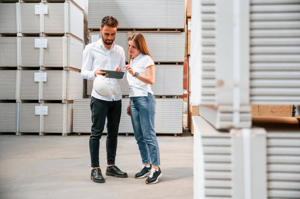 Homem e mulher dentro de um armazém de Self Storage, conversando sobre dados apresentados no tablet