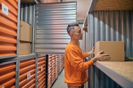 Colaborador em armazém self storage concentrado colocando mercadorias em box de armazenamento