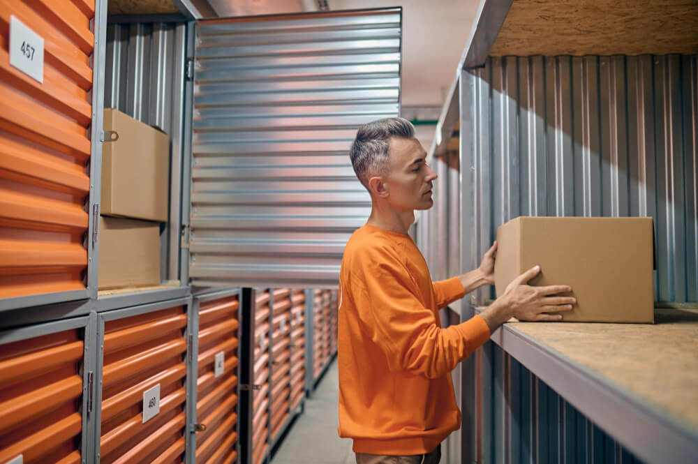 Colaborador em armazém self storage concentrado colocando mercadorias em box de armazenamento